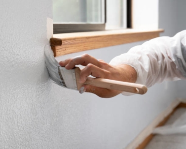 professional painter cutting in around a window frame